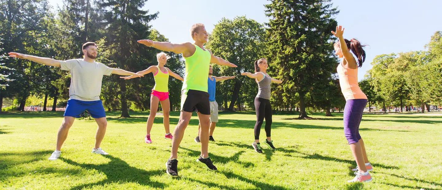 A group of people doing yoga poses outside.