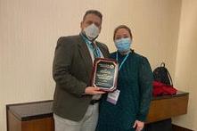 A man and a woman holding an award plaque